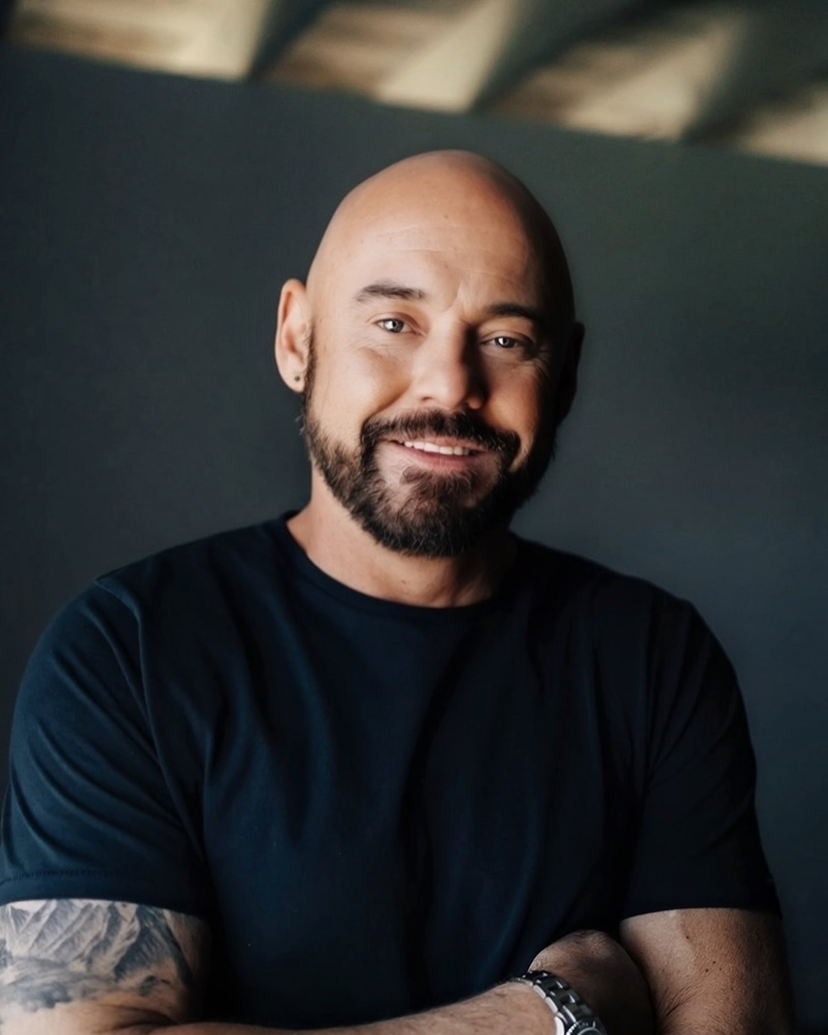 Shawn Feurer, creator of The Inner Blueprint, arms folded, in a dark studio