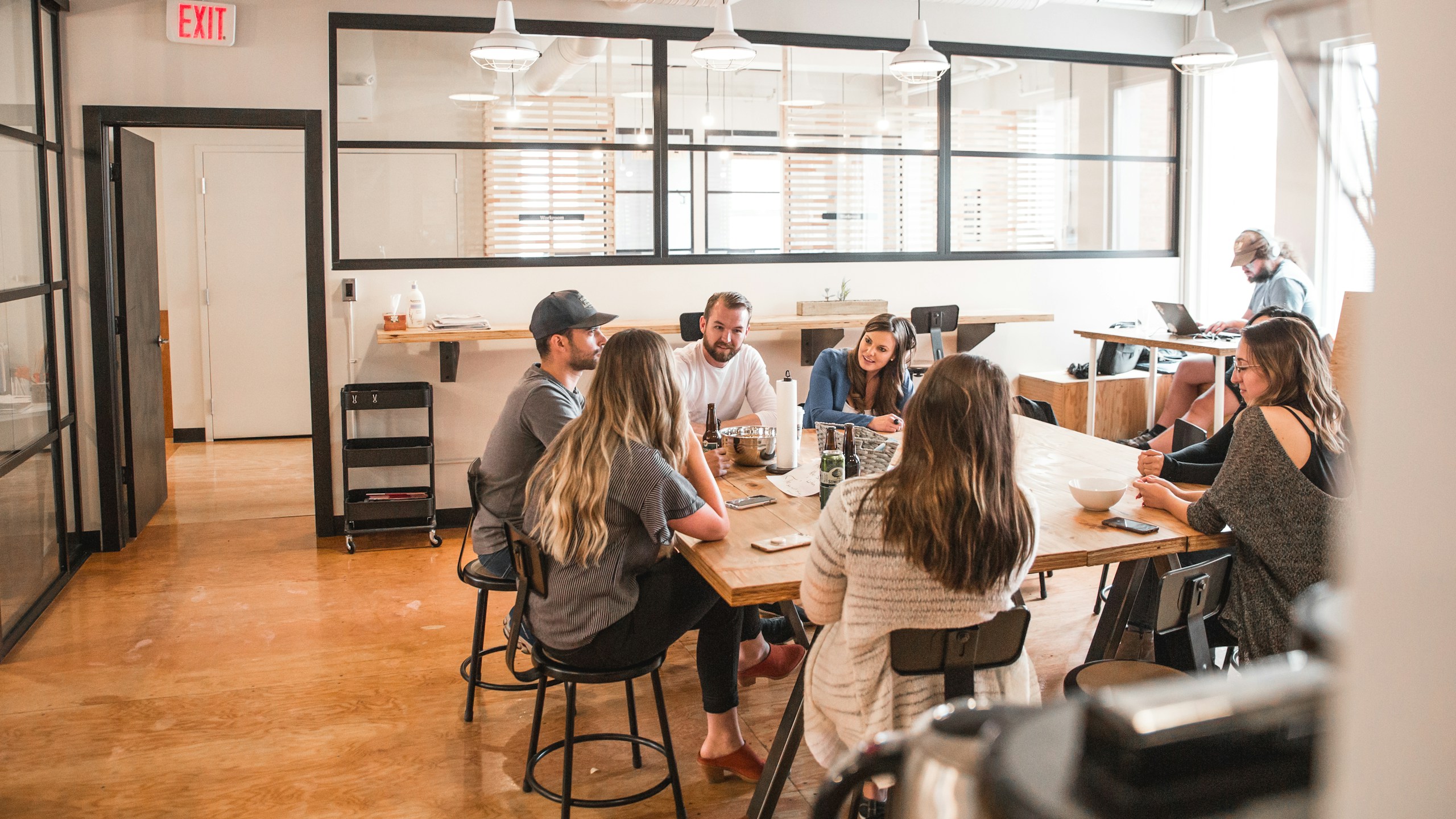 A small group exchanging ideas around a wooden table in a light-filled studio