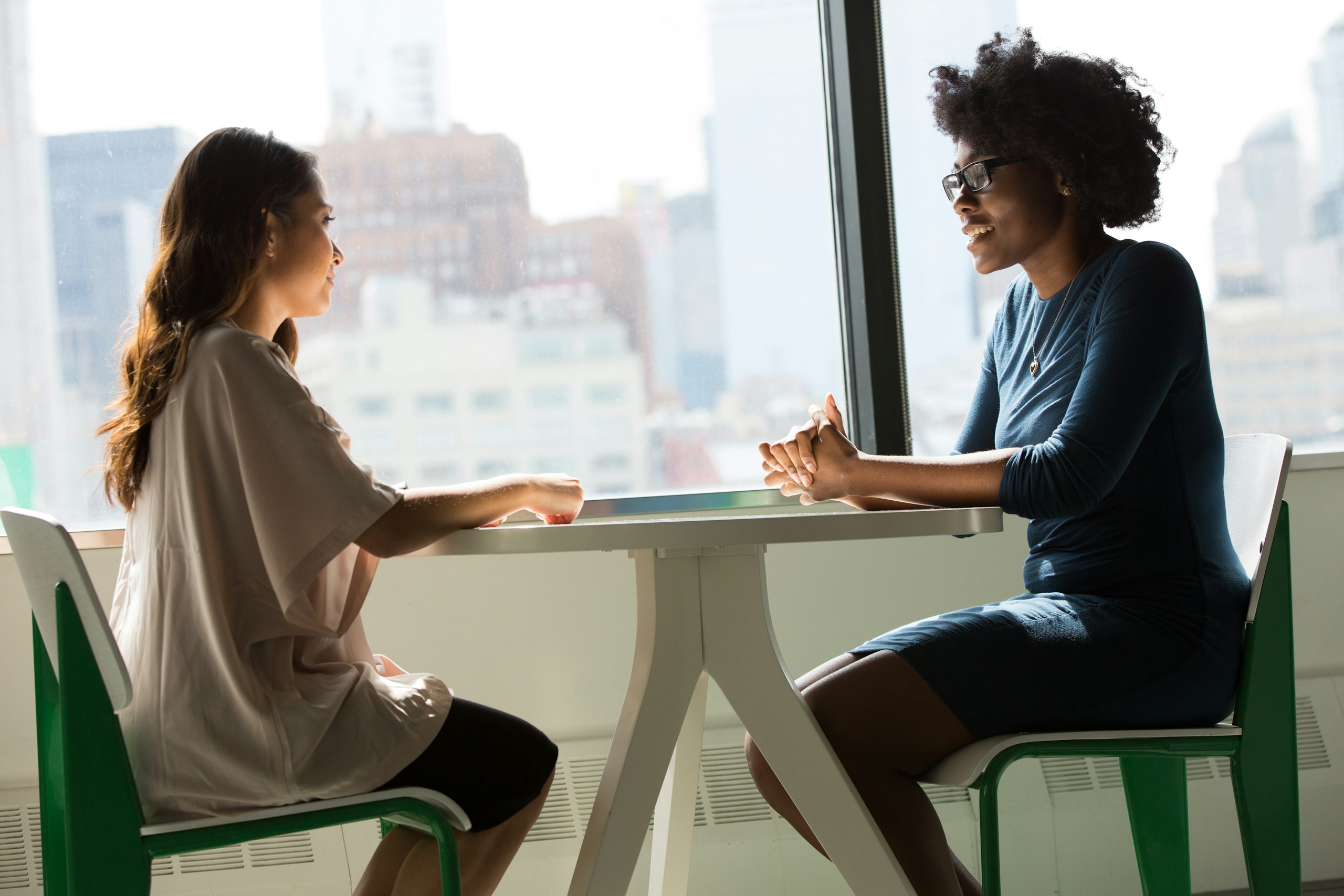 Two women having a focused one-to-one conversation beside a window